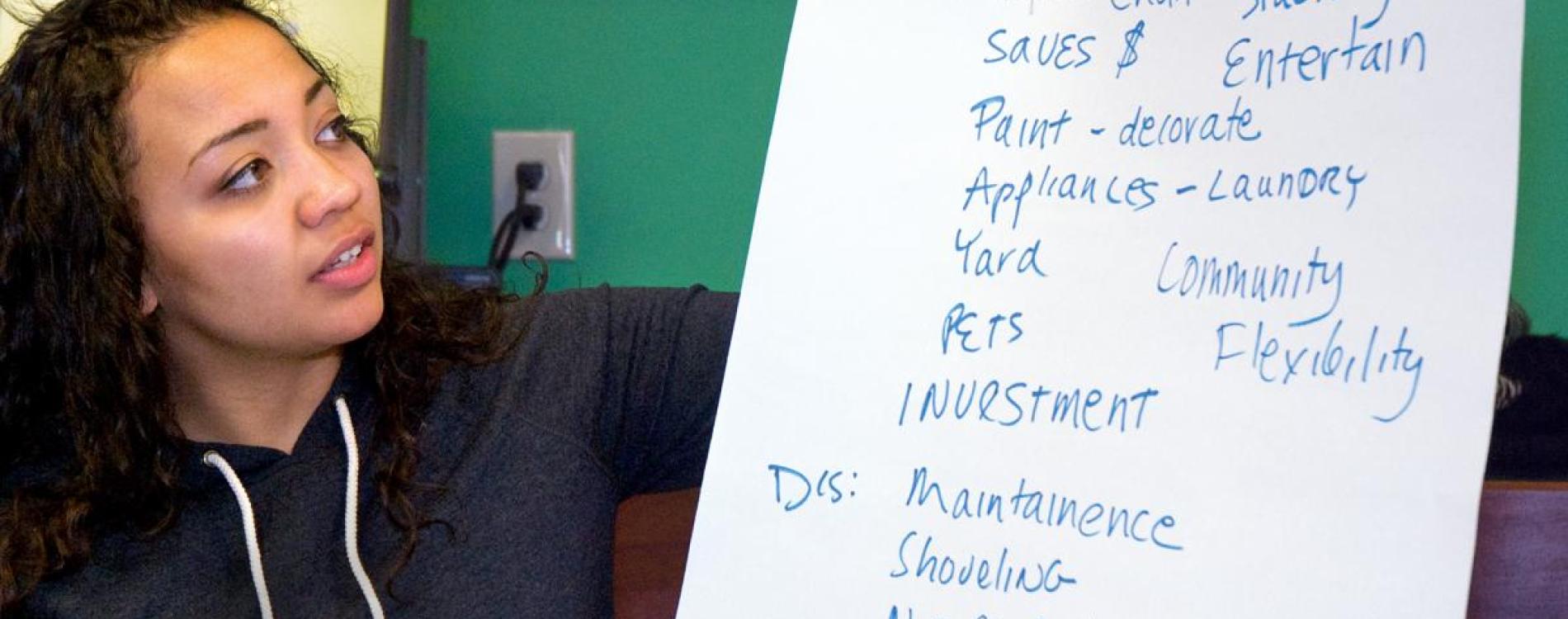 Woman examining easel sheet with notes on financial literacy